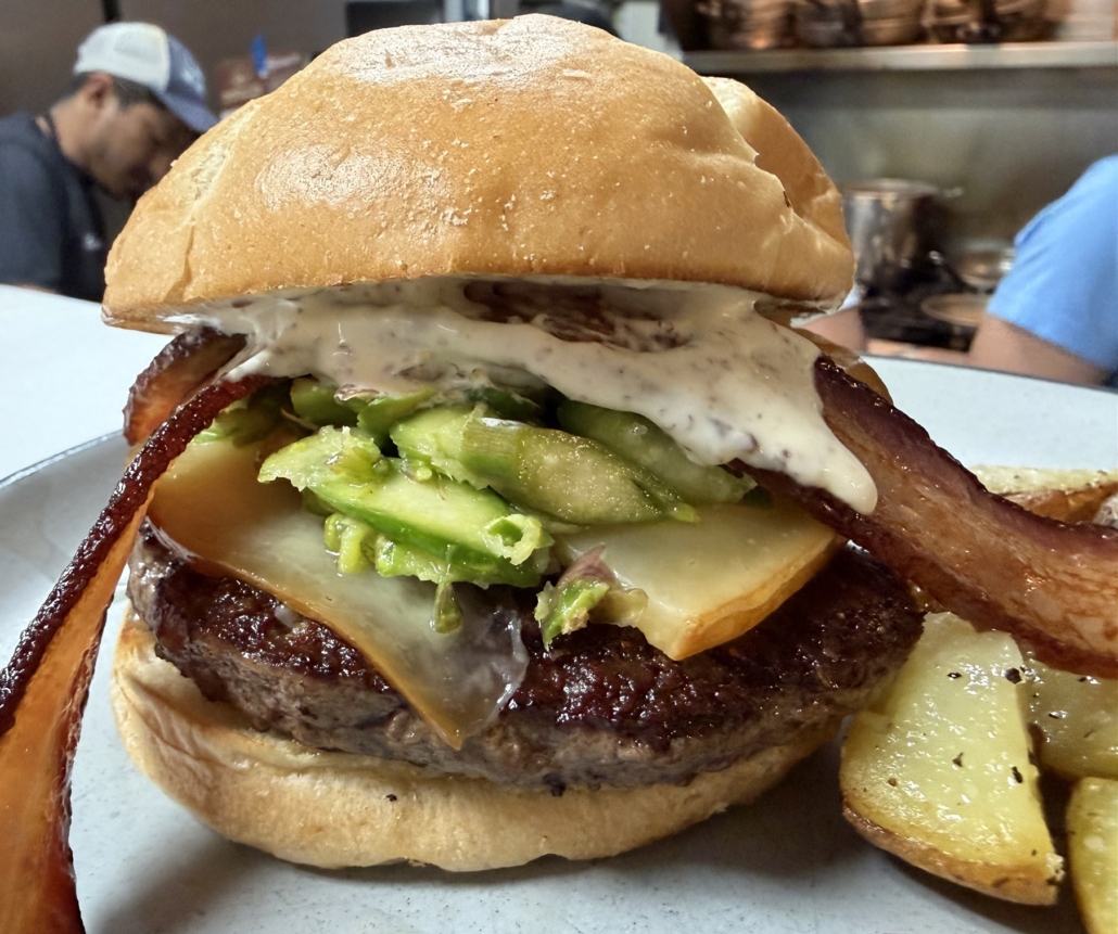 April burger - Smoked gouda melting into a perfectly seared patty… maple-kissed onions… shaved asparagus bringing that first whisper of spring… and a whole grain mustard crème fraîche tying it all together on a toasted brioche bun… finished with local, thin-cut bacon—crispy, salty, just enough to make everything else sing.